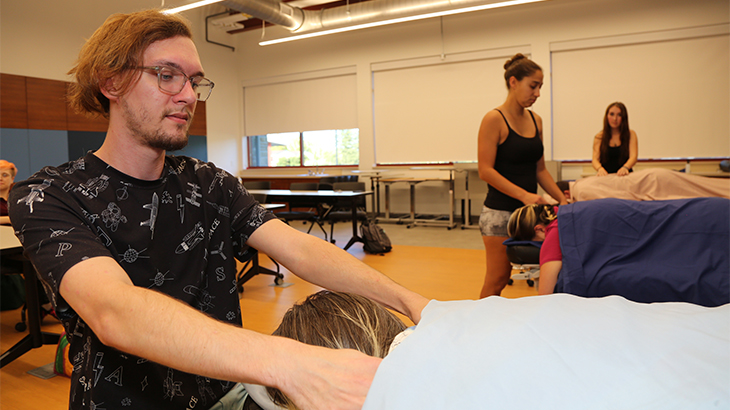Image: photo of a massage therapy student massaging the shoulders of a client on a massage table