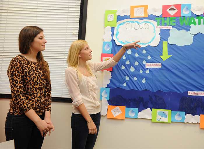 Two child development students giving a presentation on the water cycle 