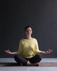 woman doing yoga with legs crossed sitting on a mat